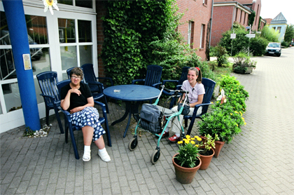 zwei Frauen sitzen auf Gartenstühlen und lachen