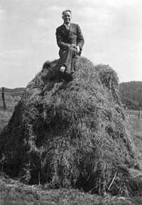 Ein Mann sitzt auf einem Heuhaufen in einer ländlichen Gegend